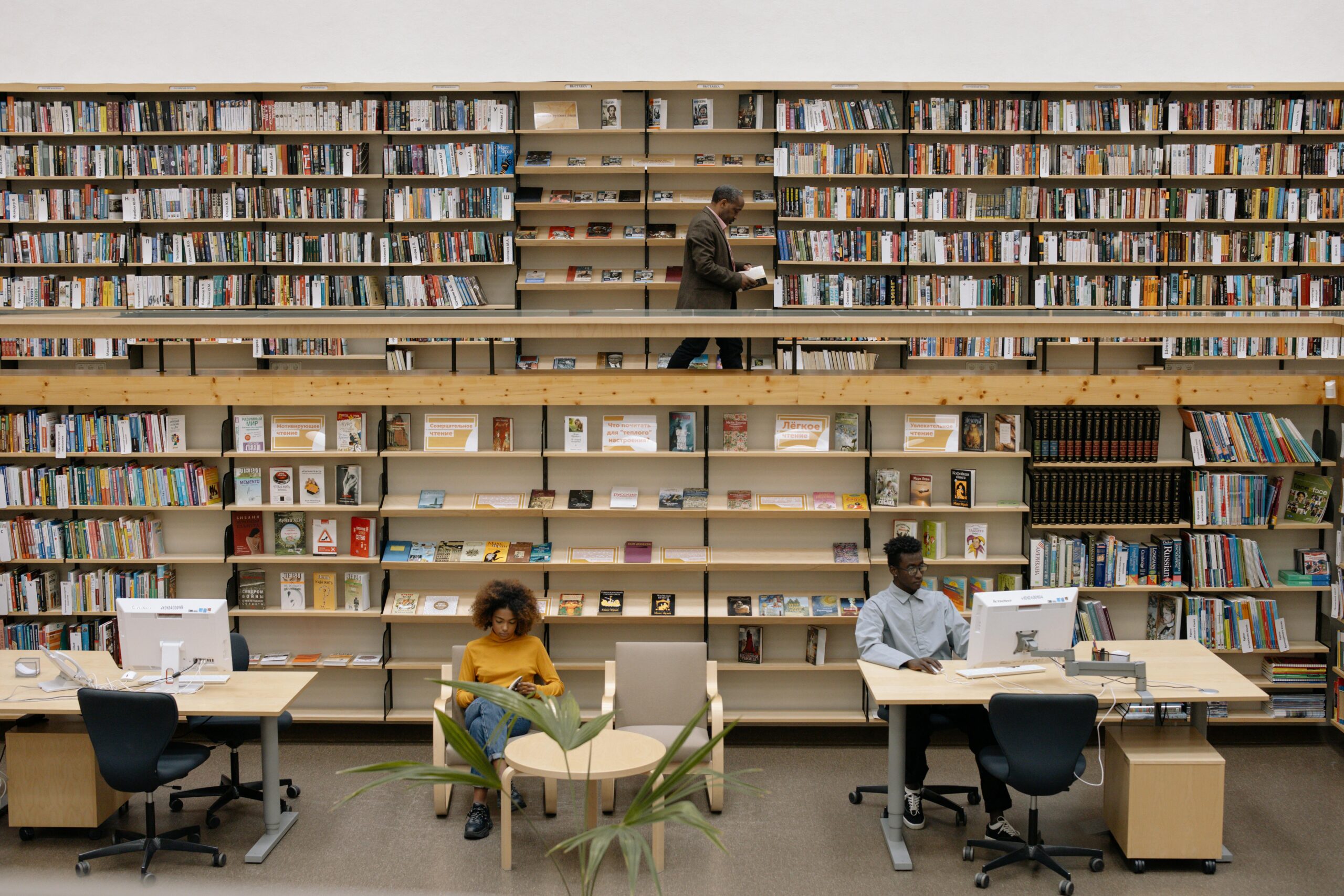 A spacious library with shelves, computers, and visitors reading and studying.